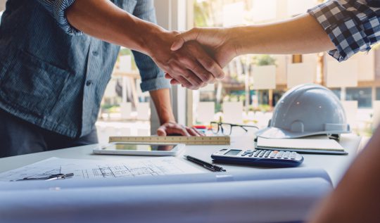 Architect and engineer construction workers shaking hands while working for teamwork and cooperation concept after finish an agreement in the office construction site, success collaboration concept.